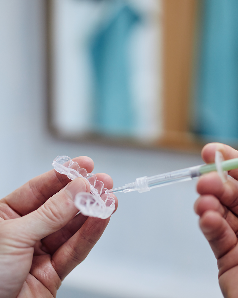 A whitening tray being filled from a syringe